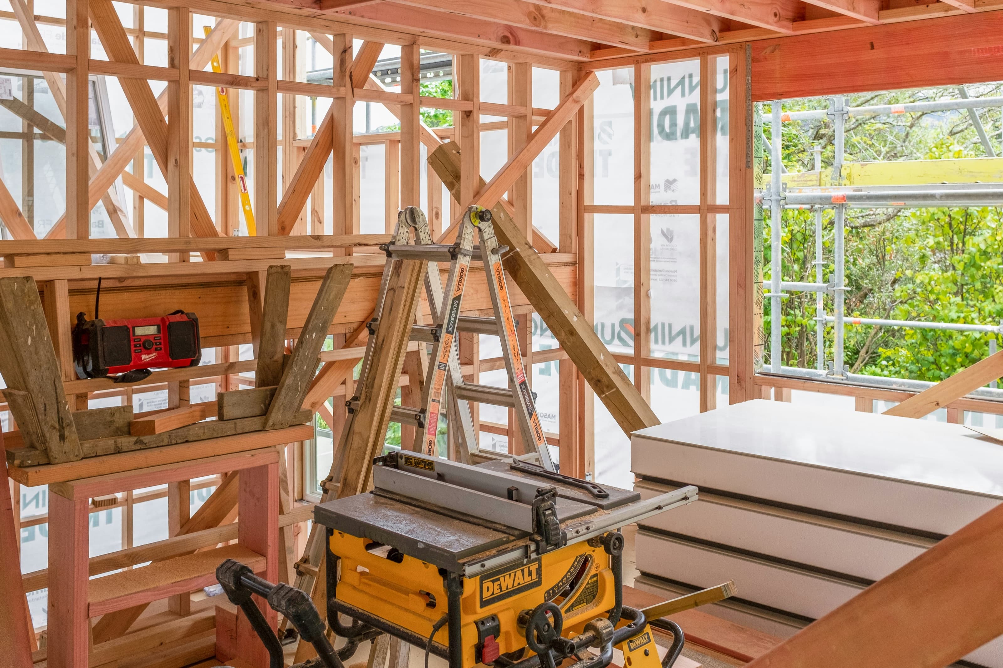 Matériaux et outils disposés dans une ossature de bois en cours de construction.